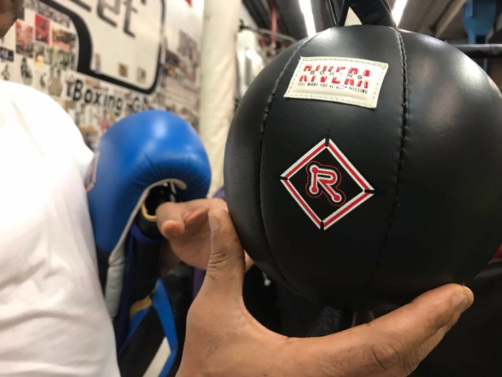 Freddy holding a speed bag with riveraboxing logo
