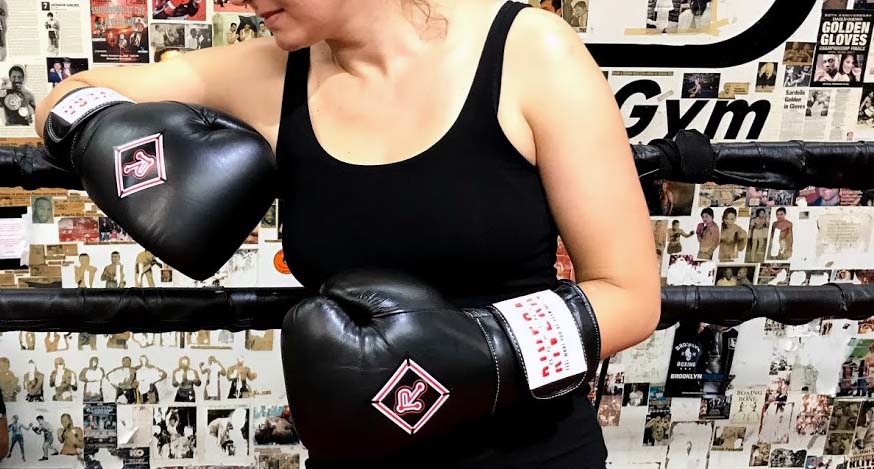 female wearing black boxing gloves with riveraboxing logo